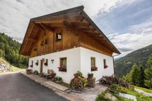 a house in the mountains with flowers in front of it at Wieserhof Ferienwohnung Priml in Sarntal