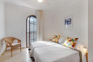 a white bedroom with a bed and a chair at Casa Fama con piscina privada clima in Yaiza +36 photos