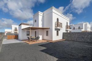 a white house with a table and a fence at Casa Fama con piscina privada clima in Yaiza