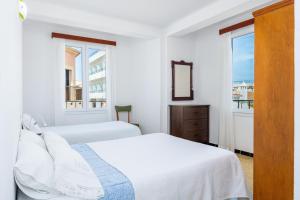 a white bedroom with two beds and a window at Brisas Vista Mar in Sa Ràpita