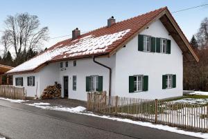 a white house with green windows and a fence at Armenhaus 1828 in Görisried