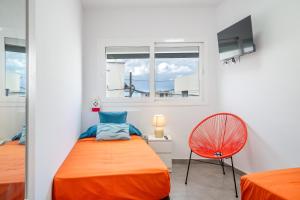 a bedroom with a bed and a chair and two windows at Sparrow in La Santa