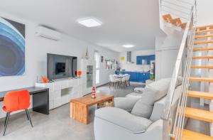 a living room with white furniture and a staircase at Sparrow in La Santa