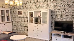 a living room with a tv and a white cabinet at Ferienwohnung Schöntal in Ludwigswinkel