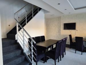 a dining room with a table and chairs and a staircase at Apartmani Gradac in Valjevo