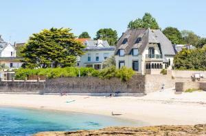 a group of people on a beach with houses at Résidence des Saules in La Forêt-Fouesnant