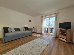 a living room with a couch and a flat screen tv at Ferienwohnung Hinterpommern - Chiemgaukarte in Inzell