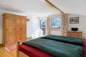 a bedroom with a bed and a dresser and two windows at Haus am See - Wohnung Jenner in Schönau am Königssee