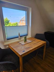 a wooden table in a room with a large window at Hus Matje in Langeneß