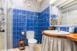 a blue tiled bathroom with a toilet and a sink at Las Candelas - Las Sopeñas in Oreña