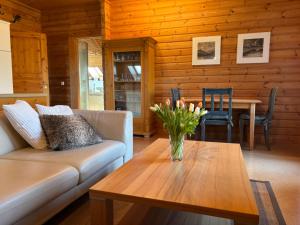 a living room with a couch and a table with flowers at Chalet am Silbersee in Frielendorf