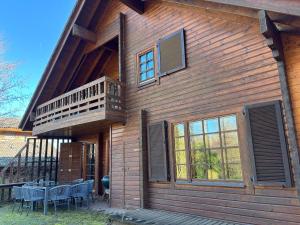 a wooden house with a balcony and a table at Chalet am Silbersee in Frielendorf