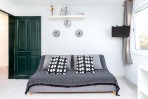 a bed with black and white pillows and a green door at Tranquilo apto con preciosa cala in Cala en Forcat