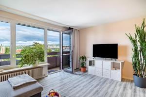 a living room with a flat screen tv and large windows at Ferienwohnung Goldstadtblick in Pforzheim