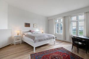 a bedroom with a bed and a desk and windows at Sophienhof in Kronprinzenkoog