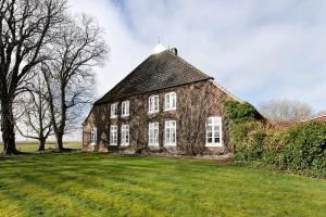an old house on a grassy field with trees at Sophienhof in Kronprinzenkoog