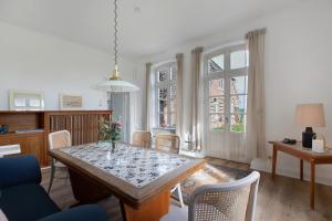 a dining room with a table and chairs and windows at Sophienhof in Kronprinzenkoog