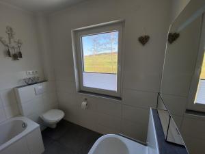 a bathroom with a sink toilet and a window at Ferienwohnung Repetal in Attendorn