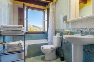 a bathroom with a toilet and a sink and a window at Casa Collado Santo Tomás in El Collado +50 photos