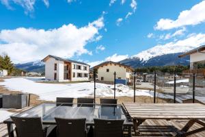 a patio with a table and chairs and snow covered mountains at Chalet Aussois Lerovi in Aussois