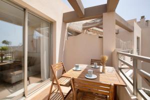 a balcony with a wooden table and chairs at Costa Bella la Tejita in La Tejita