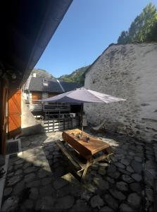 a table with an umbrella in front of a building at Gite d'Orgeix - Ax-les-Thermes in Orgeix