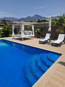 a swimming pool with two chairs and an umbrella at Casa Deco in San Borondón
