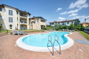 a large swimming pool with chairs and a building at Everlakegarda in Desenzano del Garda