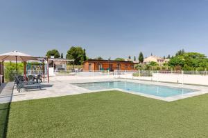 a swimming pool with an umbrella and green grass at Cortijo la Jimena 2 in Benablón