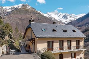 a house with a roof with mountains in the background at Gite Campbieil - Gavarnie in Gèdre