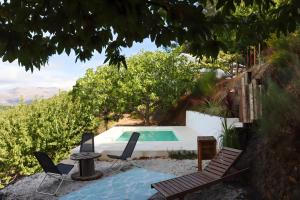 a swimming pool with two chairs and a table and a table at Cabañas Entre Castaños in Jubrique