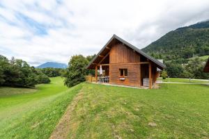 a small wooden cabin in a field with mountains in the background at Chalet Sambuy - Val de Tamié in Faverges