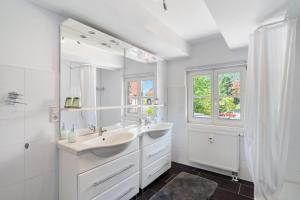 a white bathroom with a sink and a mirror at Vogtshaus de Luxe in Gernsbach