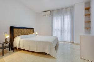 a white bedroom with a white bed and a window at Apartamento Centro con Aparcamiento in Santa Cruz de Tenerife