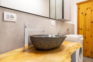 a bathroom with a large stone sink on a wooden counter at Casa Fiocco di Neve in Vigo di Cadore +19 photos