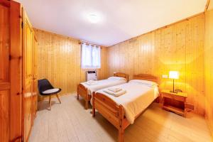 a bedroom with two beds and a chair in it at Casa Fiocco di Neve in Vigo di Cadore