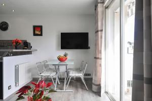 a dining room with a table and chairs and a tv at T2 Le Panorama in Cassis