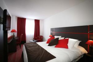 a hotel room with a large bed with red pillows at Zenia Hotel & Spa in Cambrai