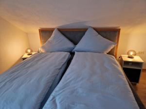 a large bed with blue sheets and pillows at Ferienwohnung Arnsberger Wald in Möhnesee