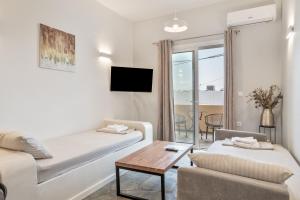 a white living room with a bed and a table at Ariston House in Porto Heli
