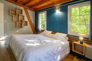 a bedroom with a white bed and two windows at Gite Au pied du Pic du Midi in Campan