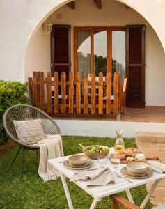 a picnic table with plates and a bowl of food on it at Costa Arenal 5 in Arenal d'en Castell