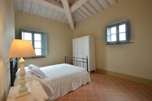 a bedroom with a bed with a lamp and two windows at Appartamento Cipresso in Trequanda