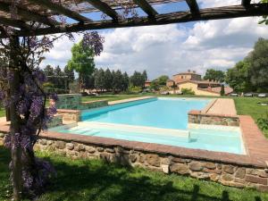 a swimming pool in a yard with purple flowers at Appartamento Cipresso in Trequanda
