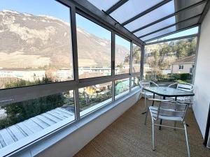 a balcony with a table and chairs in front of windows at Maison Des 3 Vallées - Wifi Véranda in Montmélian