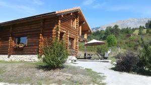 a log cabin with a table and an umbrella at Le Chalet Neige in Chorges