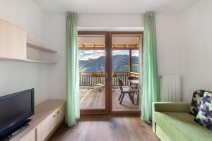 a living room with a television and a sliding glass door at Obertrisaierhof Wohnung 4 in Fie allo Sciliar