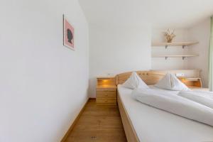 two beds in a bedroom with white walls and wooden floors at Obertrisaierhof Wohnung 4 in Fie allo Sciliar