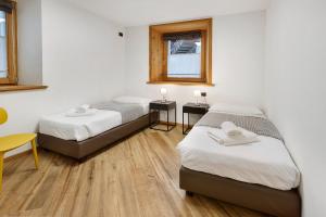 a room with two beds and a table and a chair at Appartamento Via Livigno in Isolaccia