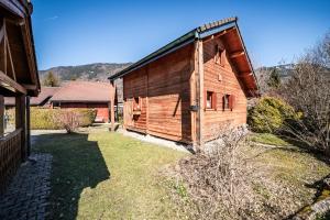 a wooden barn in a yard next to a house at Chalet 6p Simple - Patchy in Verchaix